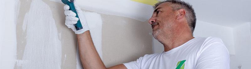 Un peintre professionnel appliquant la peinture Zolpan mat avec precision dans un interieur lumineux